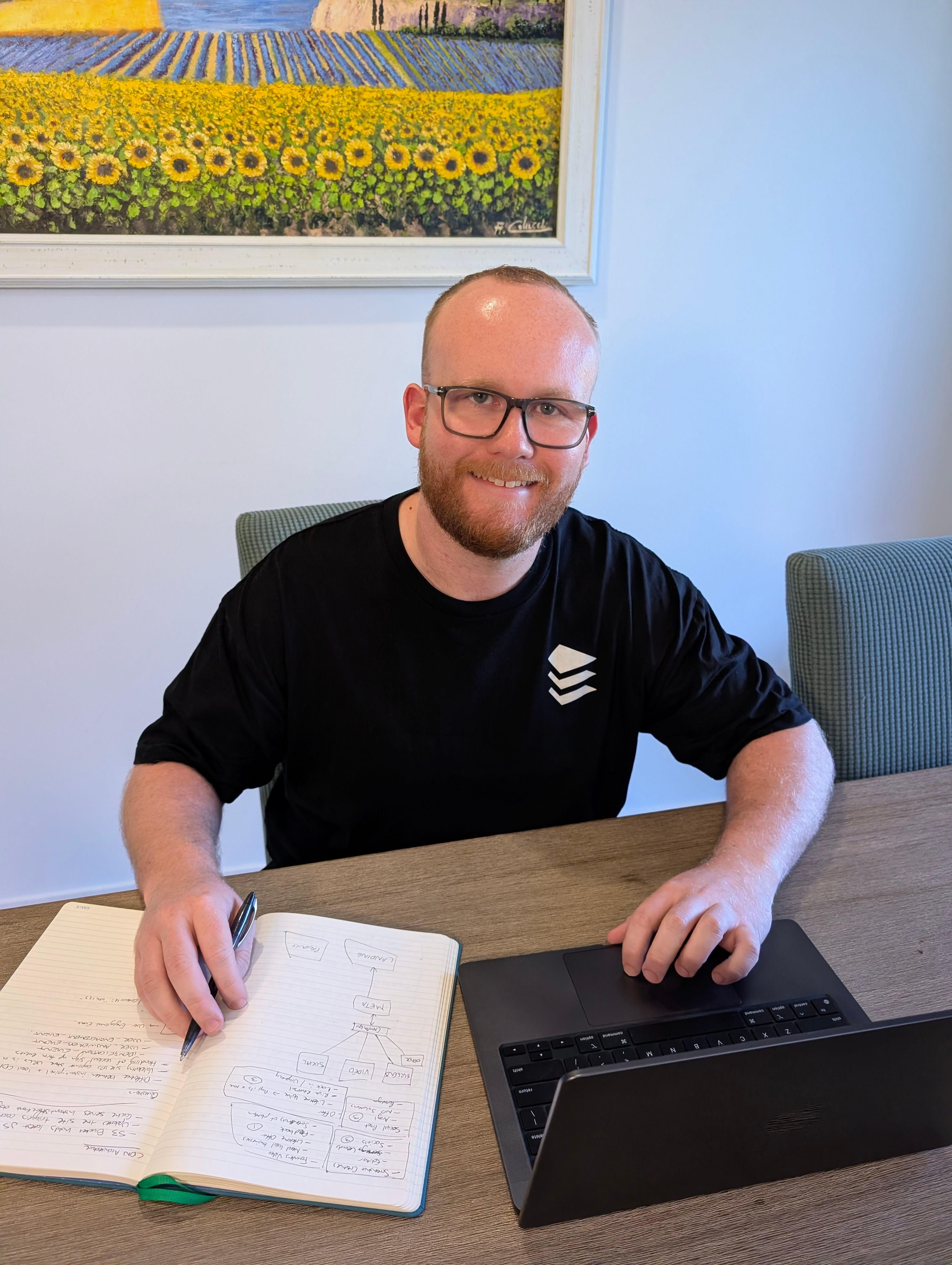 An Eminence Digital Solutions developer sketching a client project plan in a notebook next to a laptop